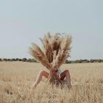 mulher num campo escondida atrás de pampas