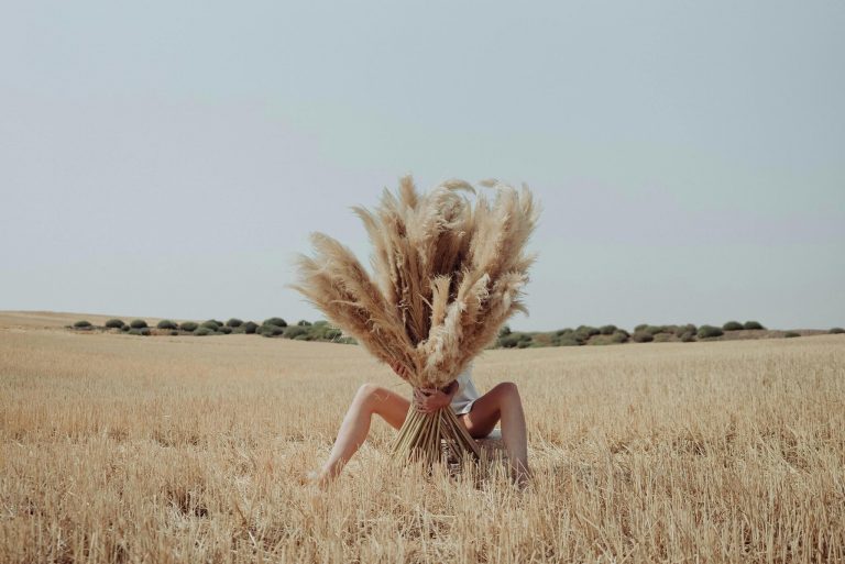 mulher num campo escondida atrás de pampas